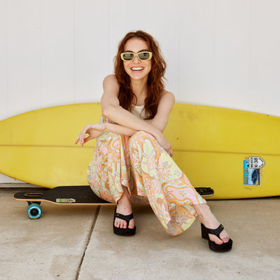 Model sitting on skateboard in front of a surfboard wearing Cobian® Zoe™ Black #color_black