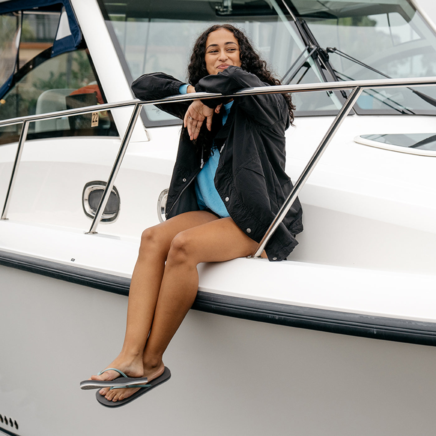 Model sitting on the edge of a boat wearing the Nias Bounce Sage #color_sage