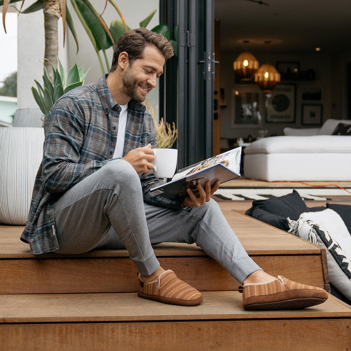 Model reading a magazine and drinking coffee while wearing the Borrego Moccasin Tan #color_tan