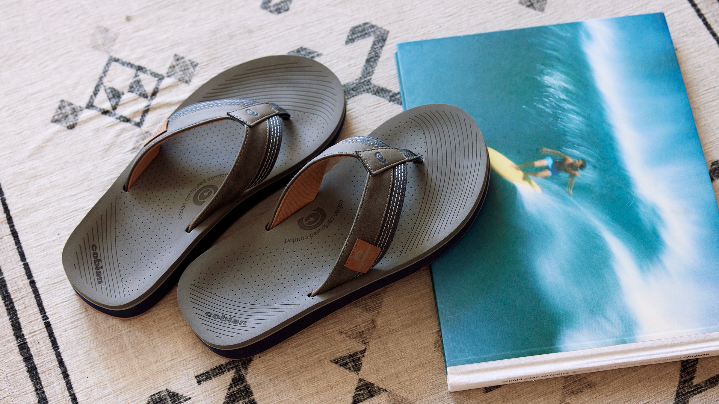 Cobian Roca Rise Grey Sandals merchandised next to a surfing book