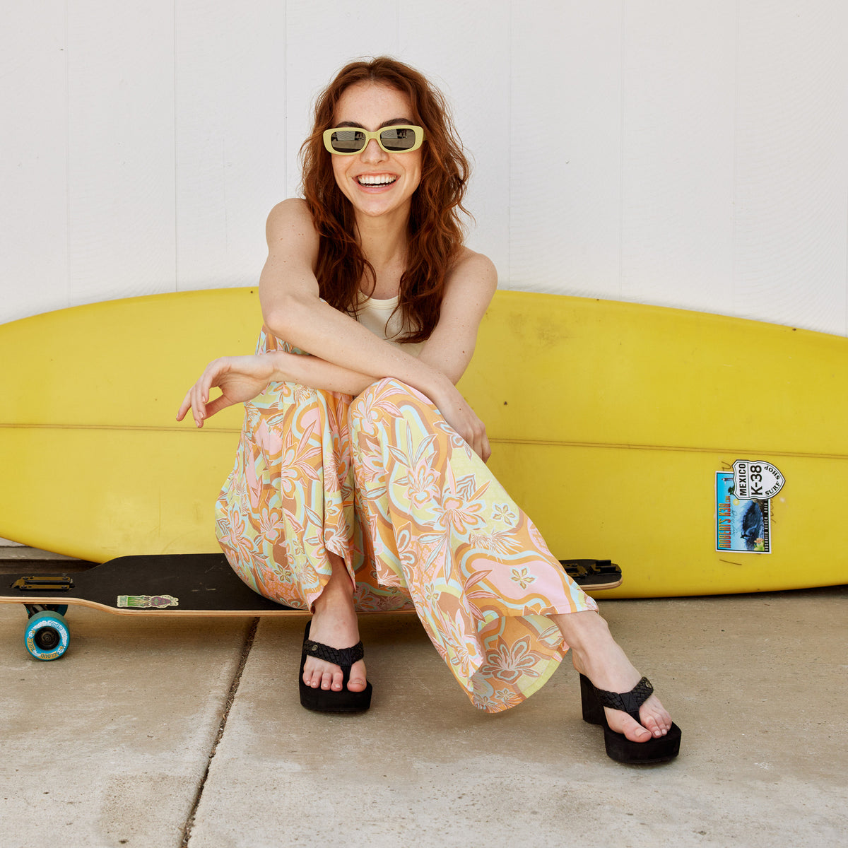 A woman sitting on a skateboard wearing the Cobian Zoe Black Wedge sandal