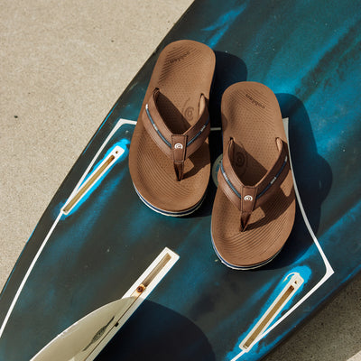 Cobian® Ponto Rise™ Brown on top of a blue colored surfboard #color_brown