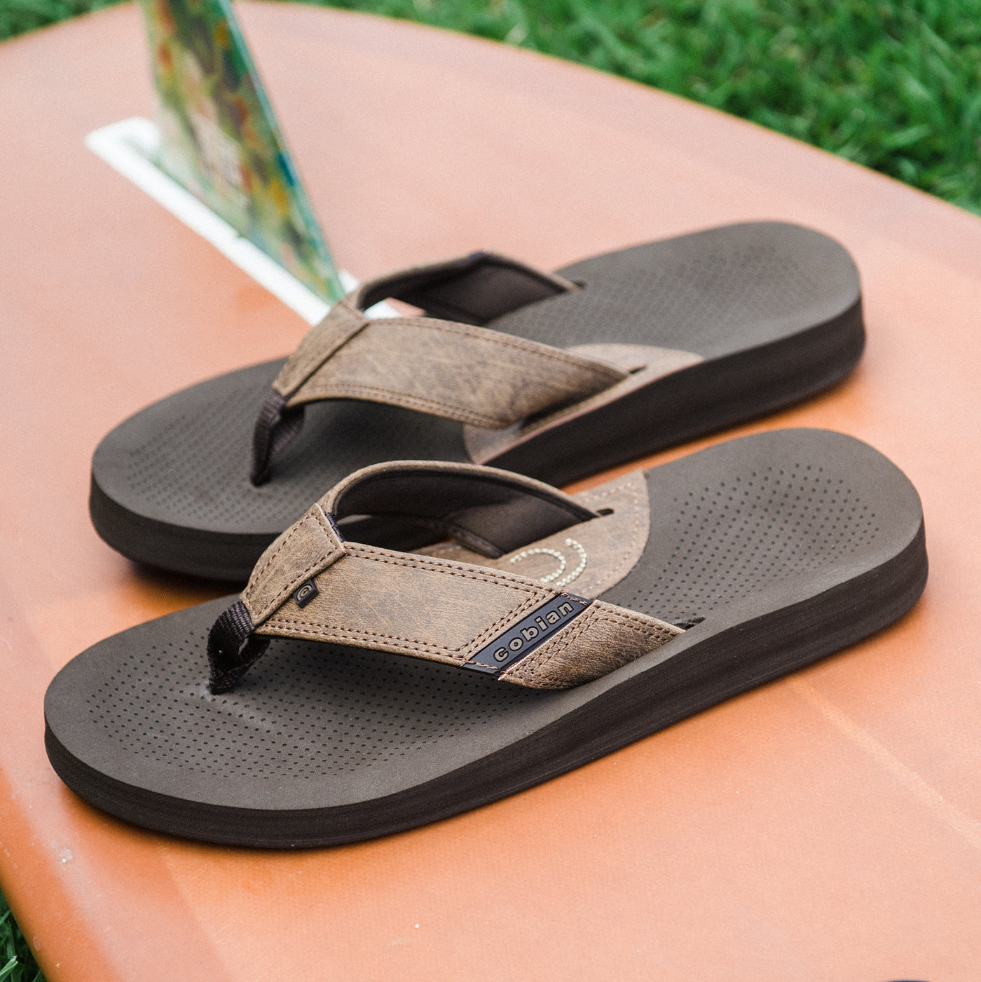 Cobian ARV 2 Java sandals on top of a surfboard #color_java