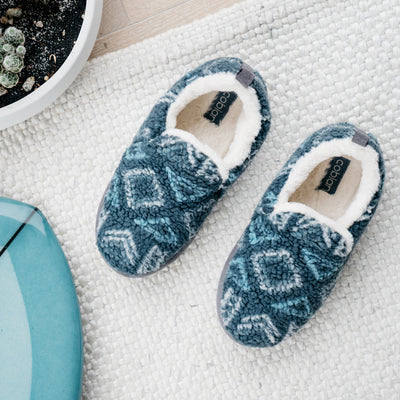 The Cobian Sonora Moccasin navy on cozy rug next to a blue surfboard #color_navy