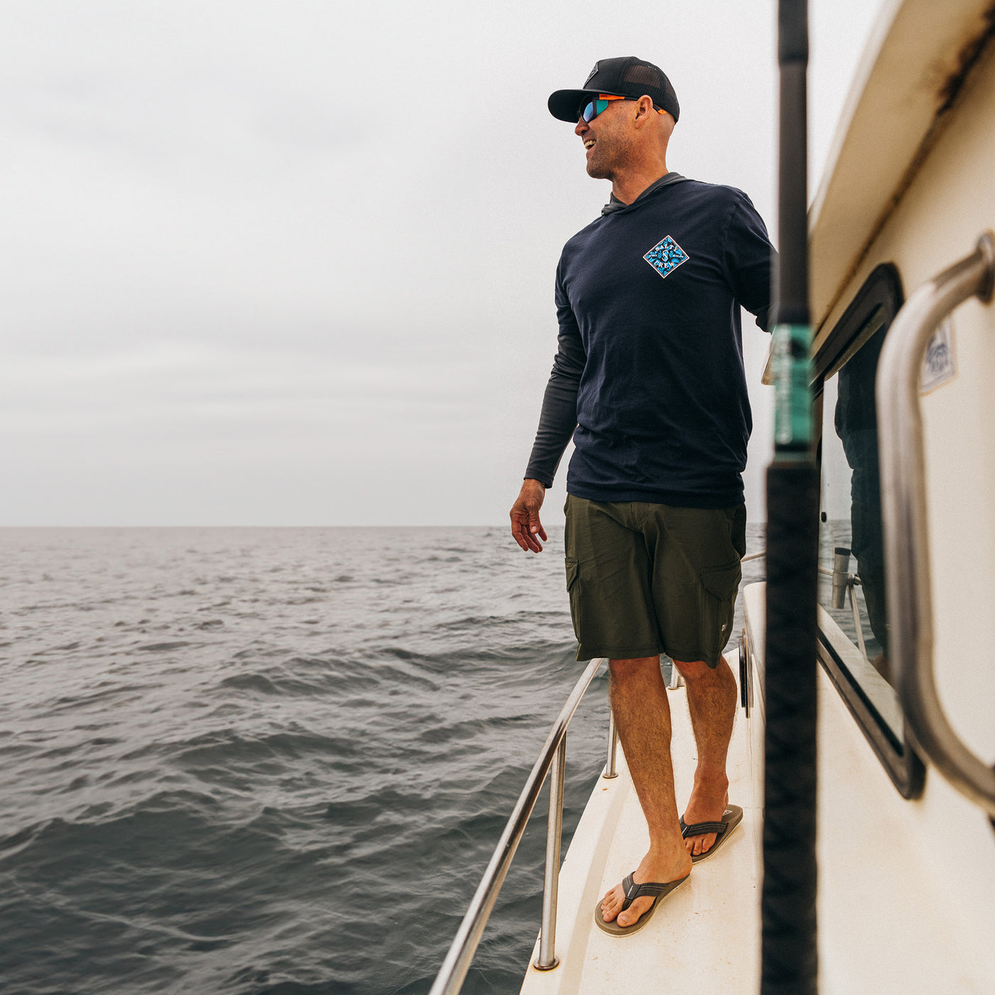 CJ Hobgood on a fishing boat deck wearing the Cobian Anchor tan sandals #color_tan