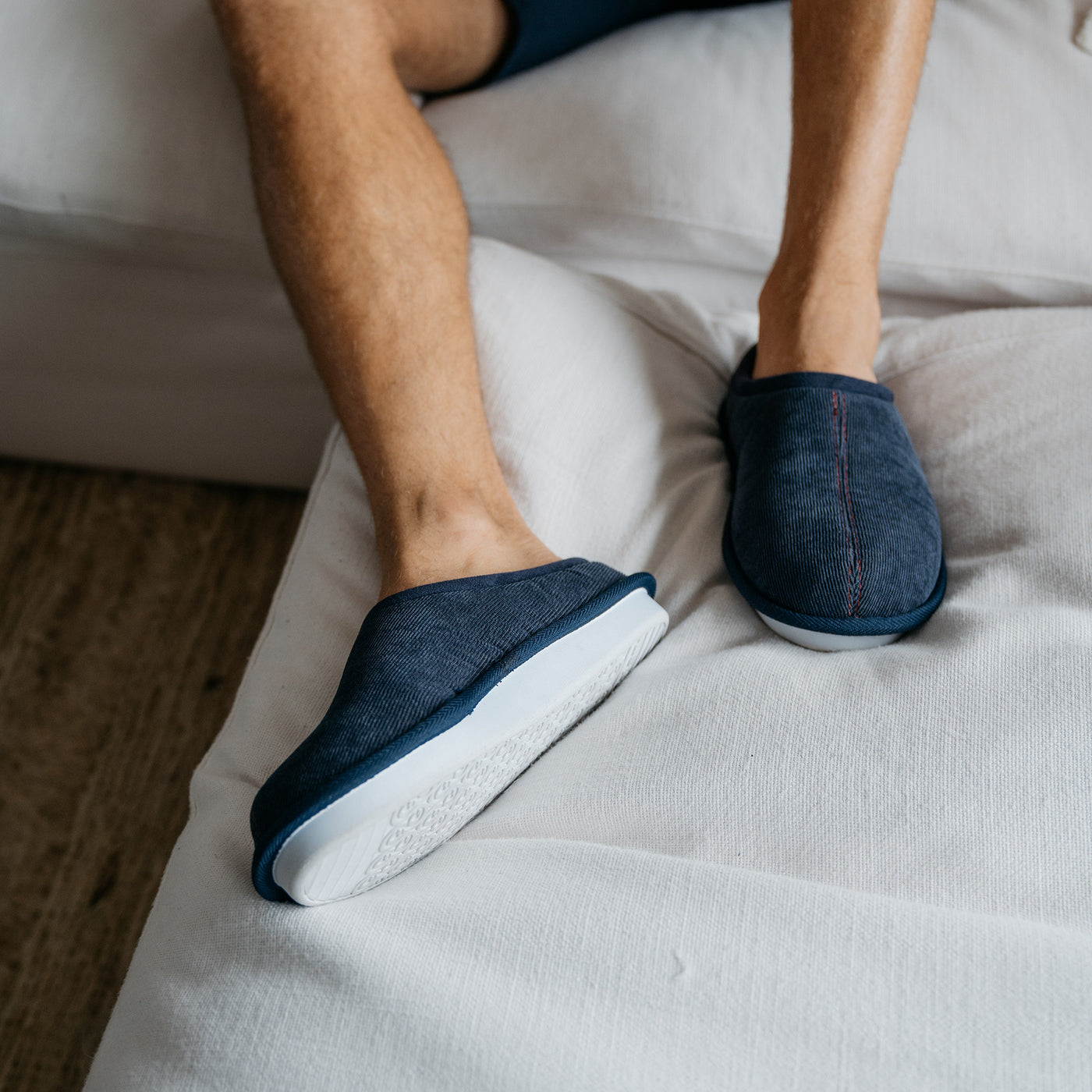 Close up of a model wearing the Cobian Dillon Slipper navy on a couch #color_navy