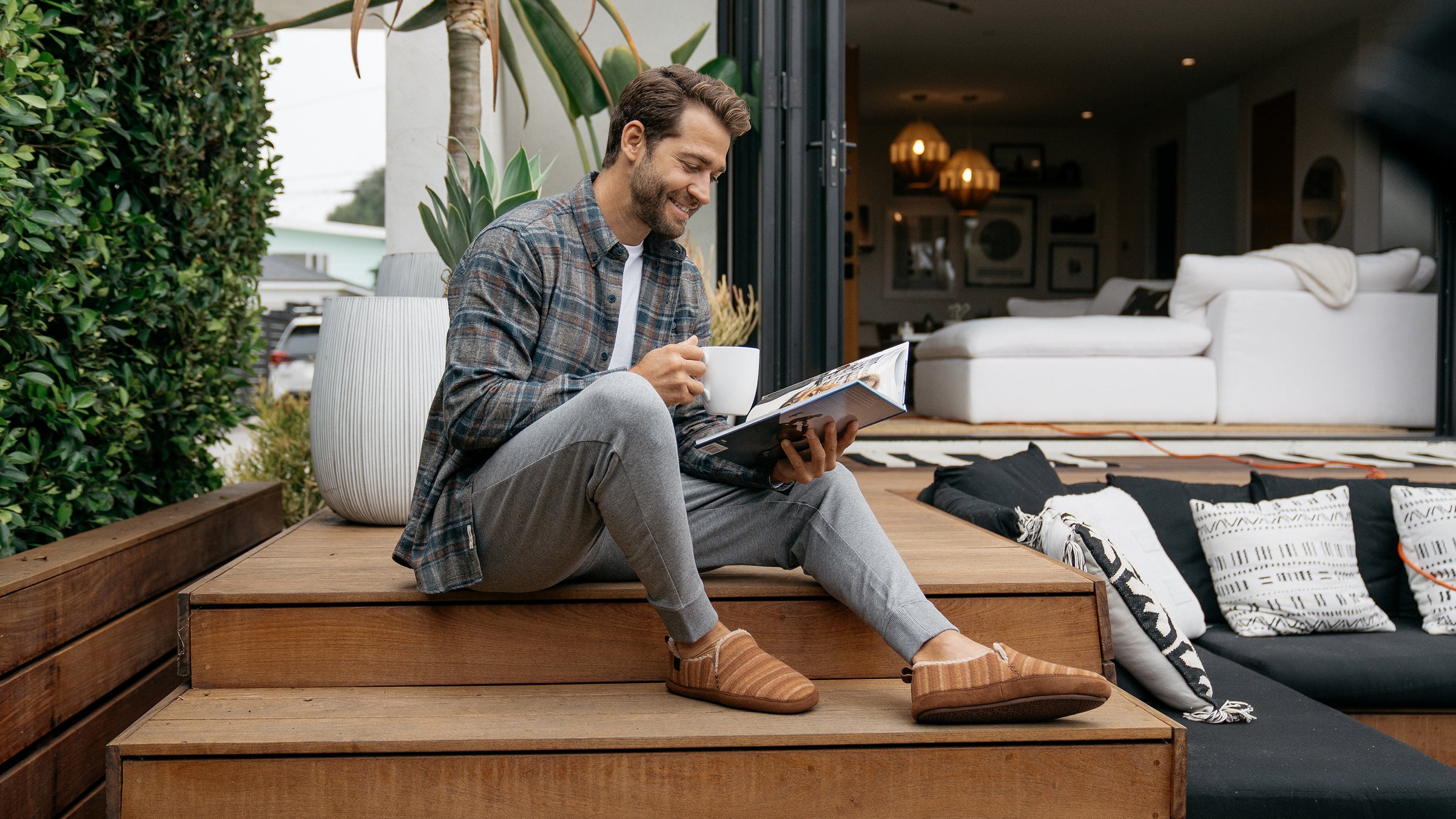 Model reading a magazine and drinking coffee while wearing the Borrego Moccasin Tan #color_tan