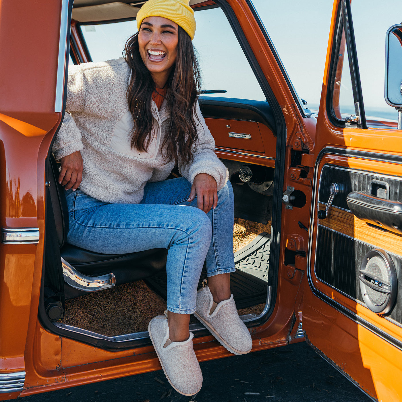 A woman wearing the Cobian Cabrillo Bootie Cream, seated in a classic pickup truck #color_cream