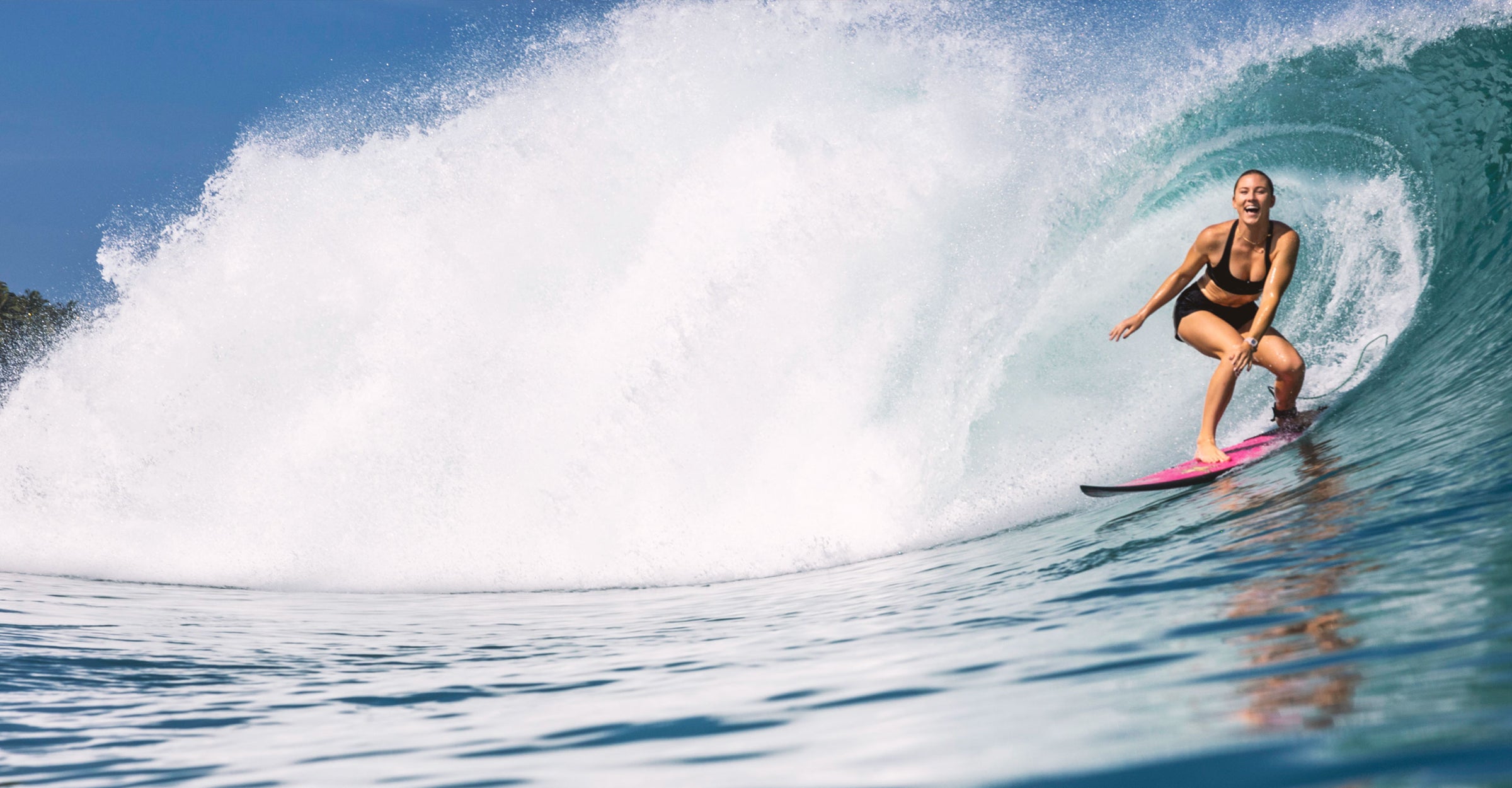 Person surfing on a wave with clear blue sky