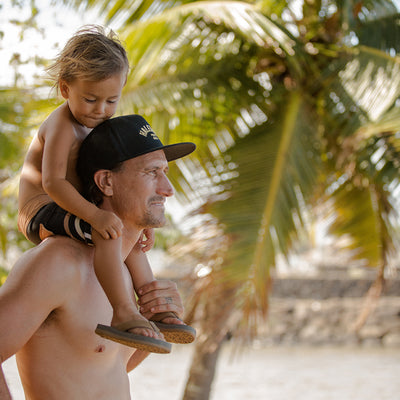 Cobian ambassador, Aaron Gold, holding his kid on his shoulders who is wearing the Floater 2 Jr. Tan #color_tan
