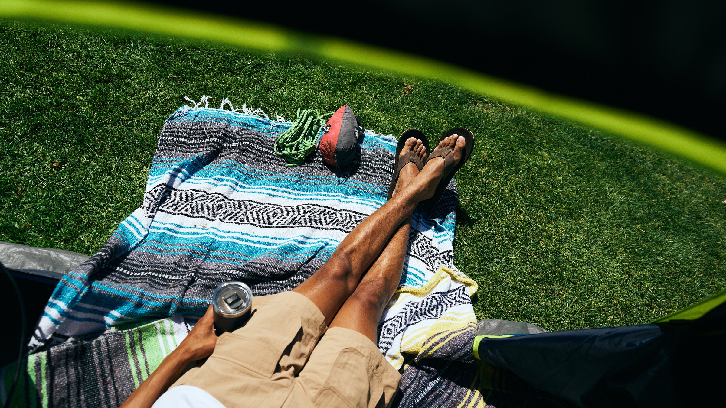 Aerial shot of model lounging in a tent next to some climbing gear wearing the ARV 2 Trek Chocolate #color_chocolate