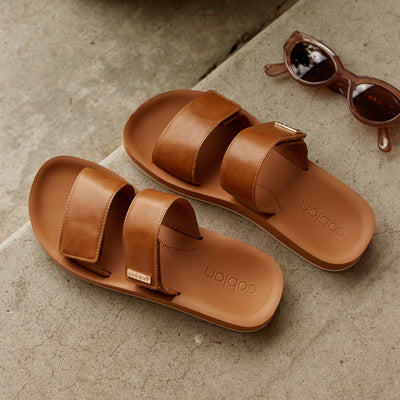 Close up of Cobian® Dana Rise™ Tan next to stylish sunglasses #color_tan