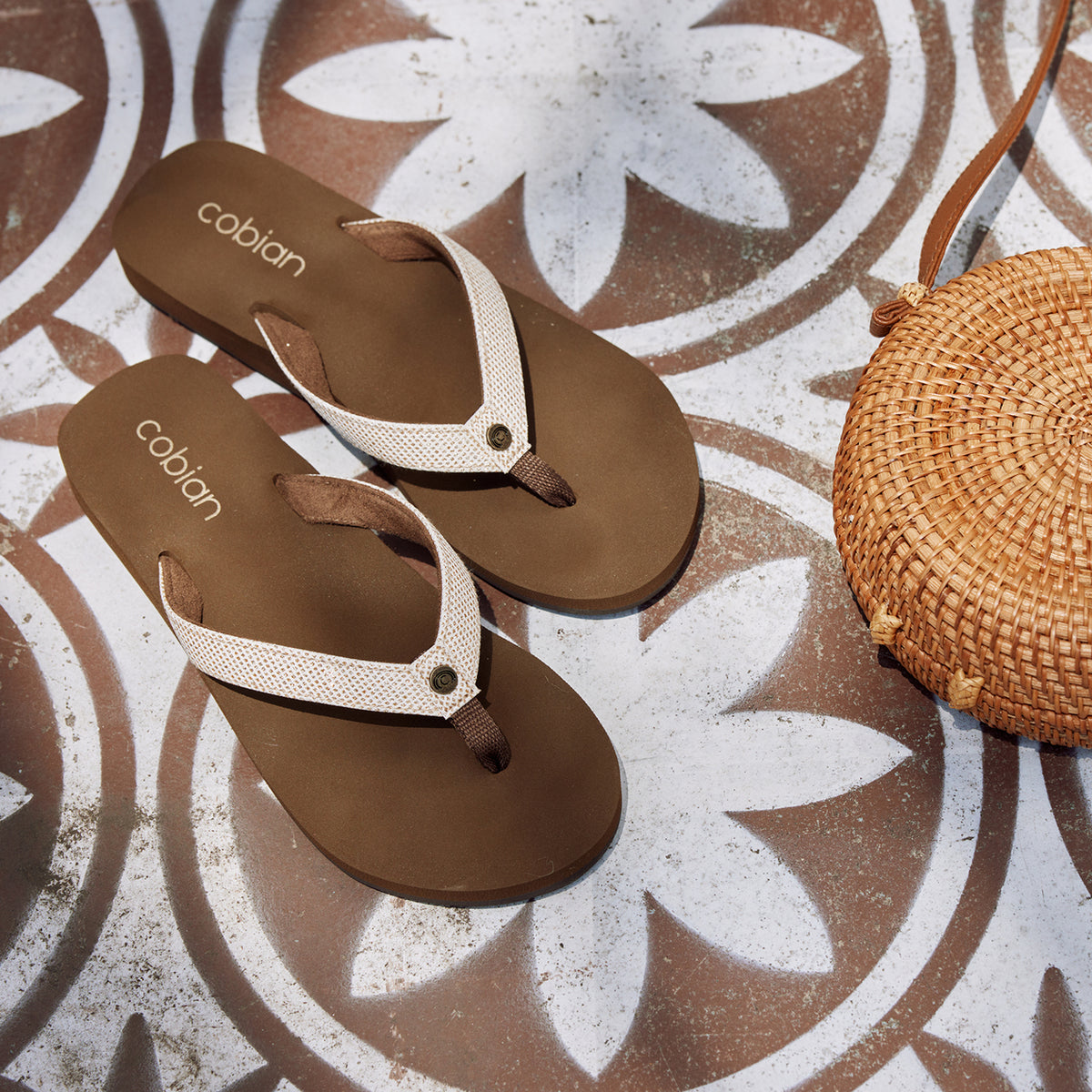 Fiesta Skinny Bounce Tan on flower patterned floor next to a woven bag #color_tan