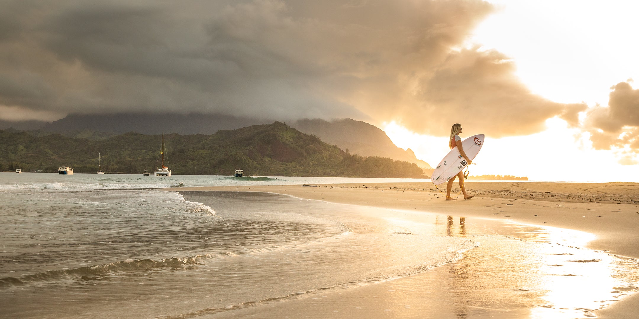 Bethany Hamilton walking the beach in Kauai with a brilliant sunset behind her